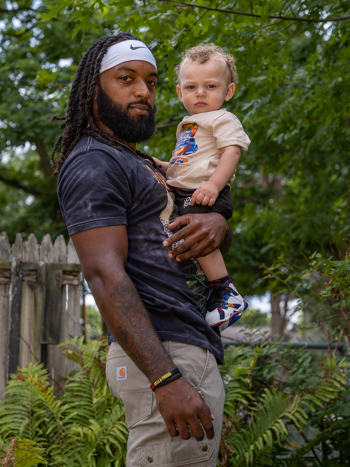 A Black man holds a young child while standing outside